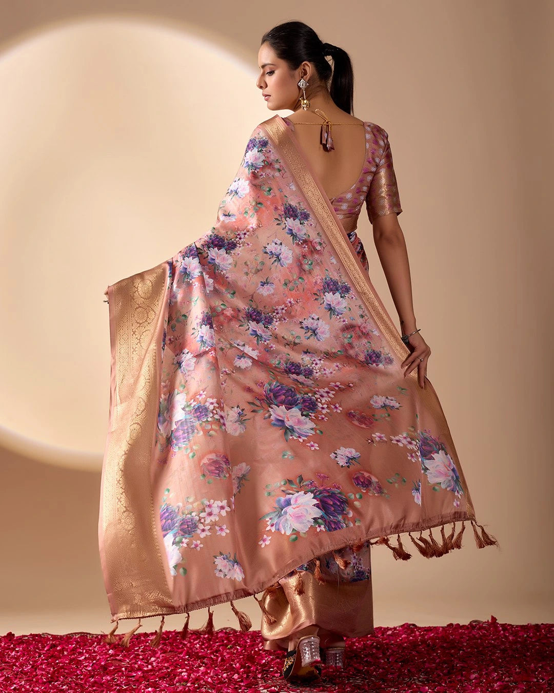 Soft pink lichi silk saree featuring a vibrant floral digital print, an elegant gold zari woven border, and tassel details by Kalyanja.